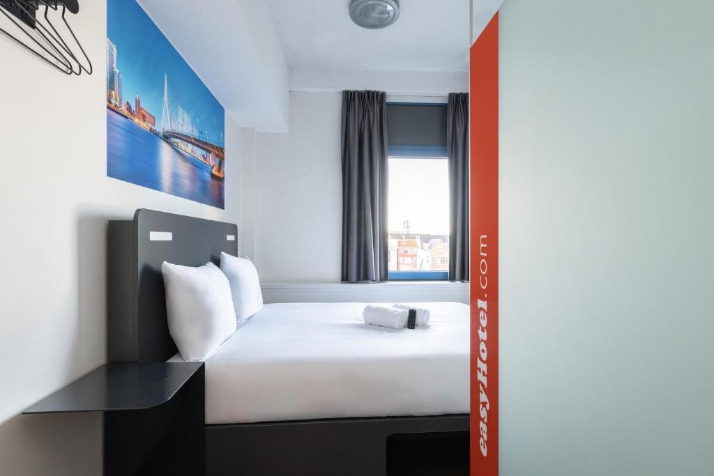 Small uniform hotel room with a fitted bed and a compact shower unit against the wall