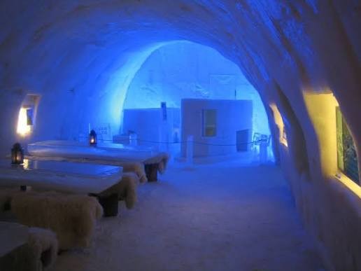 Snow hall with carved columns and benches lit in pale blue light